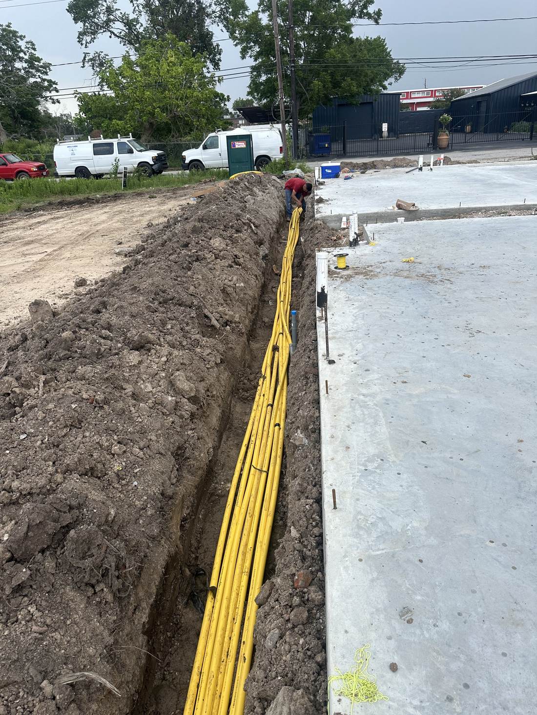Vista amplia de zanja con líneas de gas junto a losa de concreto